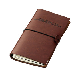 Brown TROIKA leather travel journal with 'Journal' embossed on the faux leather cover against a white background